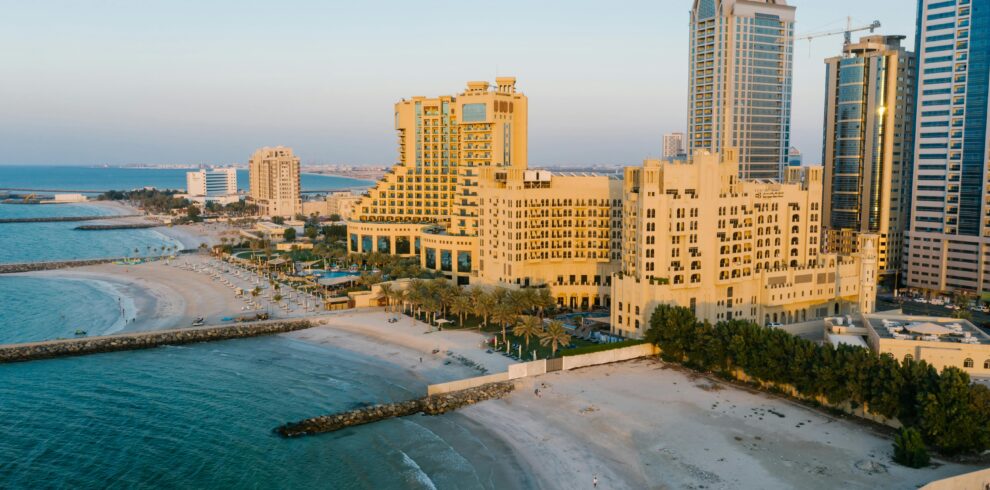 A stunning aerial view of Ajman's coastline with towering hotels and the tranquil beach at sunset.